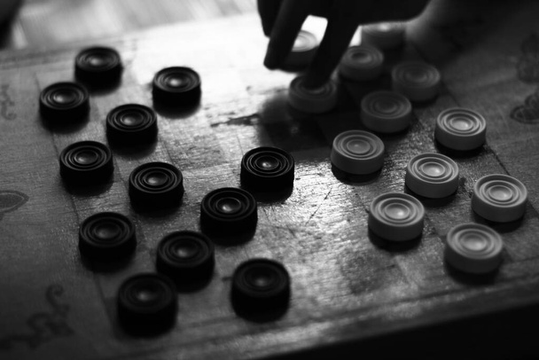 A grayscale shot of checker figures on the board, playing draughts - Valokuva, kuva