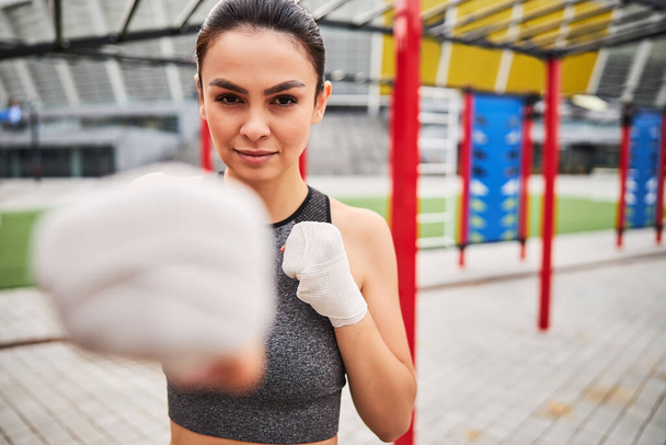 Iloinen nuori nainen harjoittelee nyrkkeilyä urheilukentällä - Valokuva, kuva