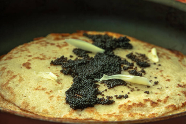 black caviar on a pancake with slices of butter - Photo, Image