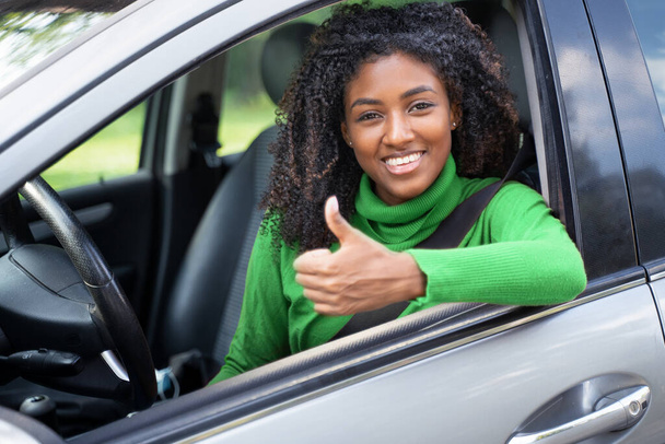 Cheerful black woman thumb up on her new car - Photo, Image