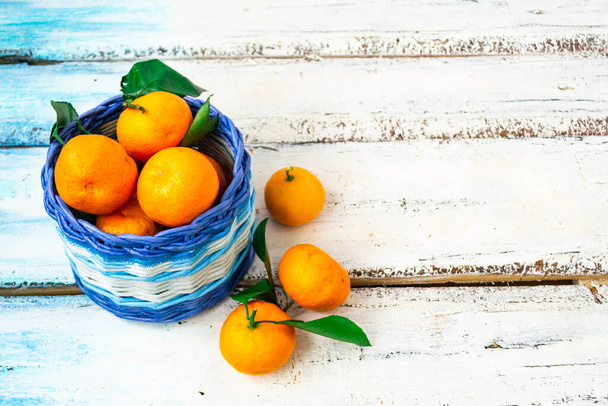 Citrus tangerines lie in a white and blue basket on a white wooden background. Christmas concept. Copy of space. - Foto, imagen
