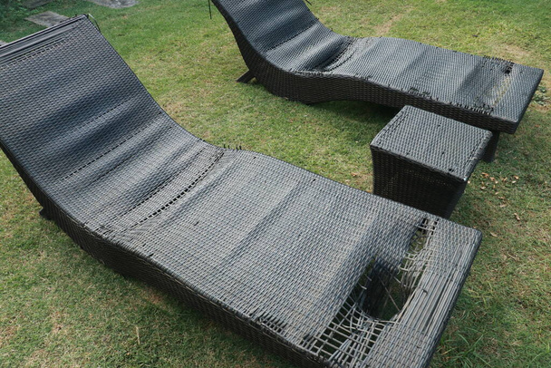 black wicker sun bed isolate with clipping path. old sunbeds in the garden. Torn pool bed on the terrace. Destroyed chair pool by the pool. - Photo, Image