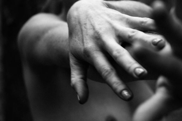 Close-up graceful pose of a beautiful woman's hands black and white photo, on the background of a naked body, back shoulders, simple and natural pose. - Photo, Image