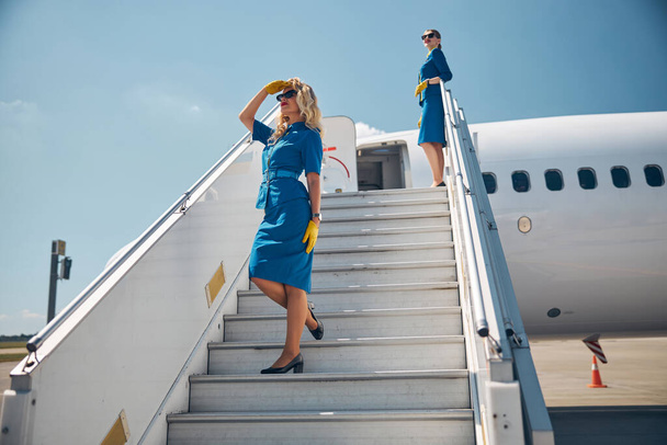 Két gyönyörű stewardess áll a repülőgép lépcsőjén. - Fotó, kép