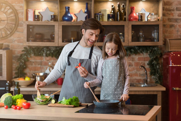 Mladý muž a jeho dcera vaří společně v kuchyni - Fotografie, Obrázek