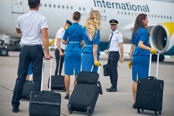 Рабочие авиакомпании, идущие по аэродрому и направляющиеся к самолету - Фото, изображение