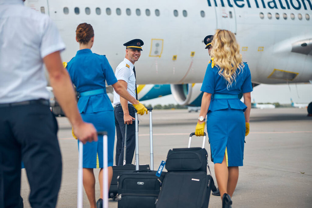 Piloten und Stewardessen mit Reisetaschen am Flughafen - Foto, Bild