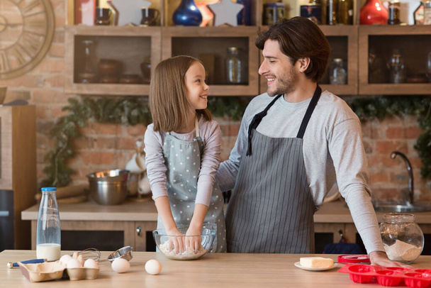 Feliz padre e hija pequeña hornear pastel en la cocina juntos, amasando la masa - Foto, imagen