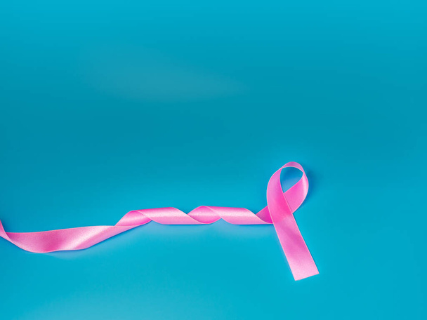 Pinkfarbenes Band auf blauem Hintergrund vermittelt das Bewusstsein für Krebs. Konzept zum Weltkrebstag. - Foto, Bild