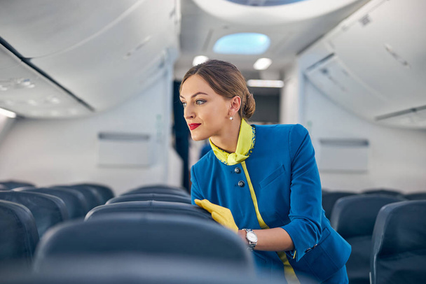 Schöne Stewardess im leeren großen Vorstand moderner internationaler Fluggesellschaften - Foto, Bild