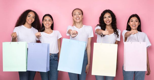 Naiset näyttää värikäs ostoskassit poseeraa yli vaaleanpunainen Studio tausta - Valokuva, kuva