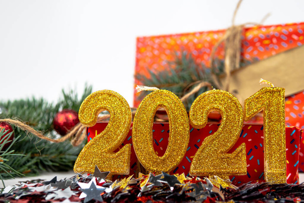 Vakantie achtergrond met de tekst van de gouden nummer 2021, confetti, geschenkdoos en kerstboom tak zijn op de achtergrond. Gelukkig nieuwjaar en vakantie concept. Selectieve focus. - Foto, afbeelding