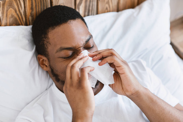 Sick African Guy Blowing Nose In Tissue Lying In Bed - Photo, Image