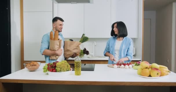 Lovely cheerful young carefree married couple which having fun together during cooking on contemporary cuisine - Video, Çekim