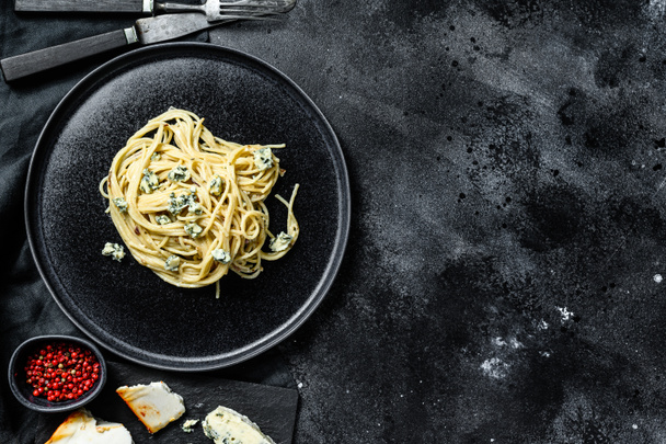 Pasta de espaguetis con salsa de queso Gorgonzola azul. Fondo negro. Vista superior. Copiar espacio. - Foto, imagen