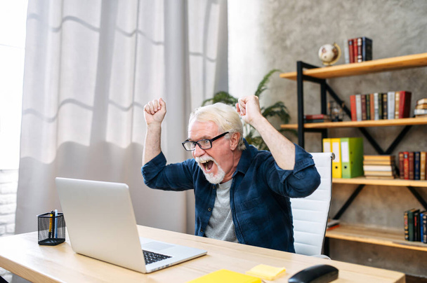 Older man is using laptop for working indoor - Фото, зображення