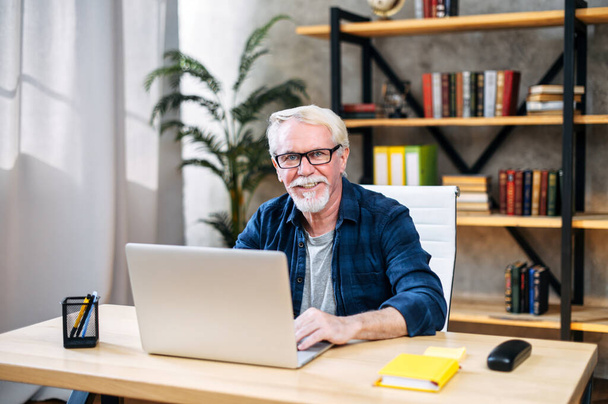 Older man is using laptop for working indoor - Фото, зображення