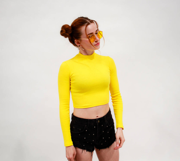 Portrait shooting of a stylish girl. Beige shades. Trends of spring and summer 2020.Black shorts and yellow top.  - Fotografie, Obrázek