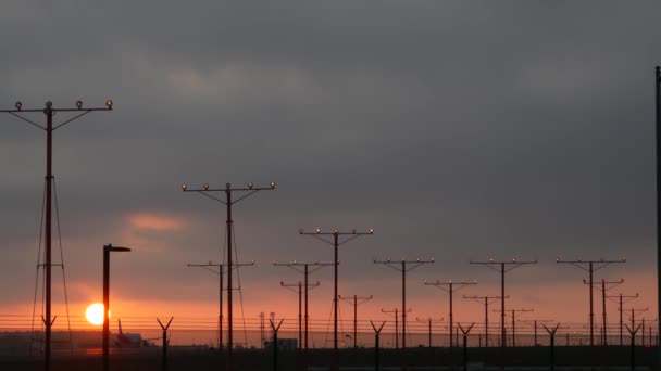 Repülőgép leszállás LAX repülőtér naplementekor, Los Angeles, Kalifornia USA. Utas- vagy teherszállító repülőgép sziluett, drámai felhős táj. Repülőgépek érkeznek a reptérre. Nemzetközi légi közlekedés - Felvétel, videó