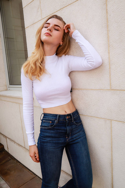 Portrait shooting of a stylish girl. Beige shades. Trends of spring and summer 2020.Black pants and white crop top.  - Фото, зображення