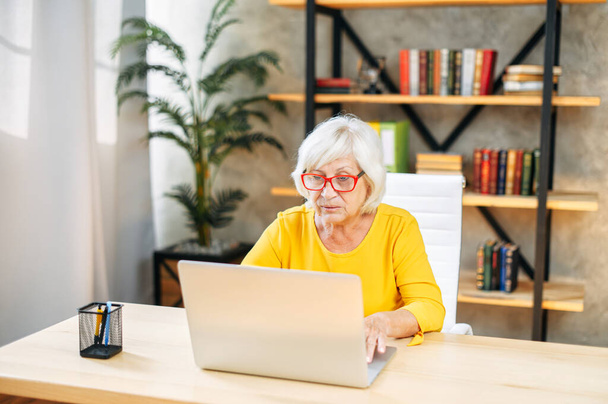 Senior woman is using laptop for work indoor - 写真・画像