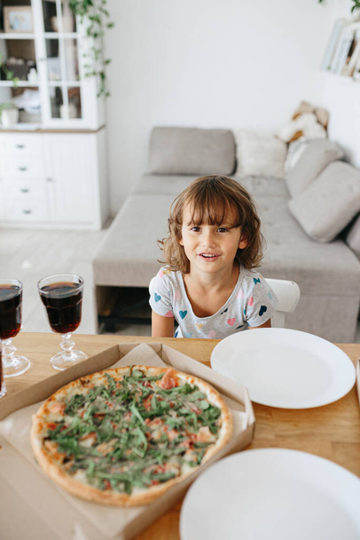 Happy time of eating concept. Kids girl eating pizza at home. Adorable childr enjoy eating pizza with a very happy emotional expressions of face - Foto, Imagen
