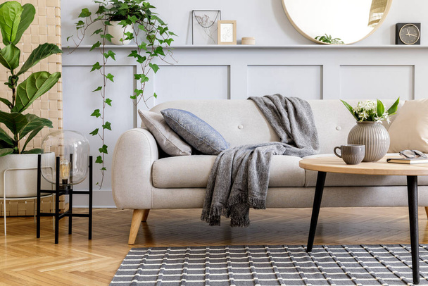 Scandinavian concept of living room interior with design sofa, coffee table, plant in pot, flowers, carpet, plaid, pillow, shelf, decoration and personal accessories in modern home staging. - Photo, Image