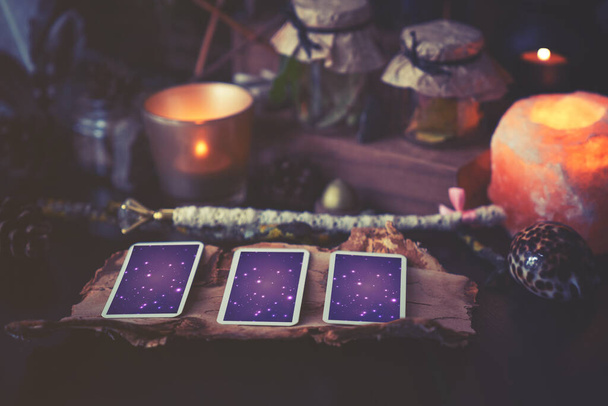3 auf einem schwarzen Tisch liegende Tarotkarten mit magischen Gegenständen. Kalte Farben im Schatten. - Foto, Bild