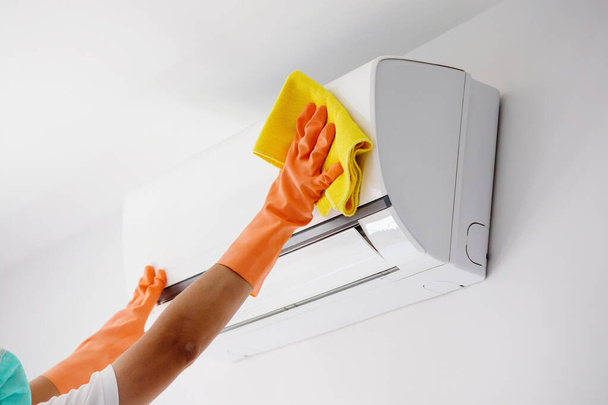 Asian man cleaning air conditioner with microfiber cloth - Photo, Image