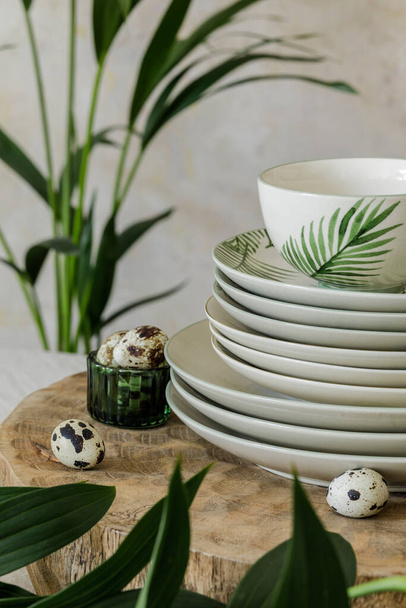 Stylish composition of beautiful plates, cups and kitchen accessories with floral pattern,  wooden tray, plants and elegant decoration. Dining concept of family table. Close up. - Fotó, kép