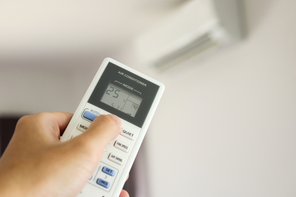 Käsi kaukosäätimellä suunnattu ilmastointilaite huoneen sisällä - Valokuva, kuva