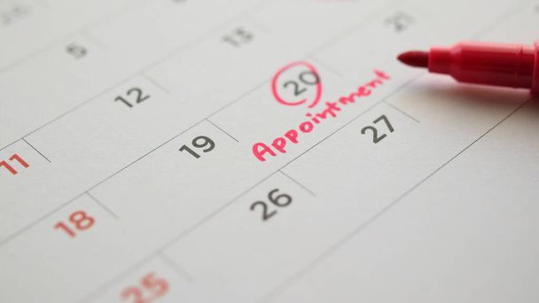 Στυλό κόκκινο χρώμα δείκτη δείχνει σε σημαντικό χρονοδιάγραμμα ραντεβού σε λευκό ημερολόγιο ημερομηνία της σελίδας close up - Φωτογραφία, εικόνα