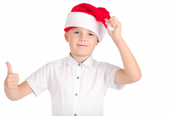Portrait de geste heureux jeune garçon dans le chapeau de Père Noël avec pouce vers le haut isolé sur fond blanc - Photo, image
