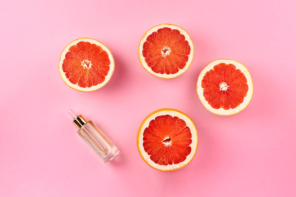 Composition with grapefruit slices and bottle of essential oil on pink background - Fotó, kép