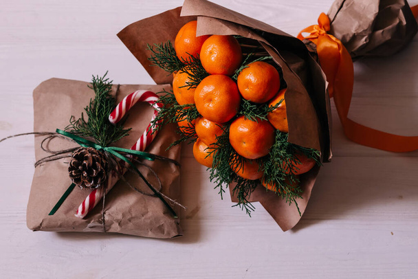 ramo con ramas de abeto y naranjas frescas con regalo en la mesa - Foto, imagen