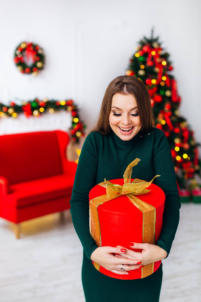 Felice eccitato giovane donna in possesso di scatola regalo sullo sfondo dell'albero di Natale - Foto, immagini