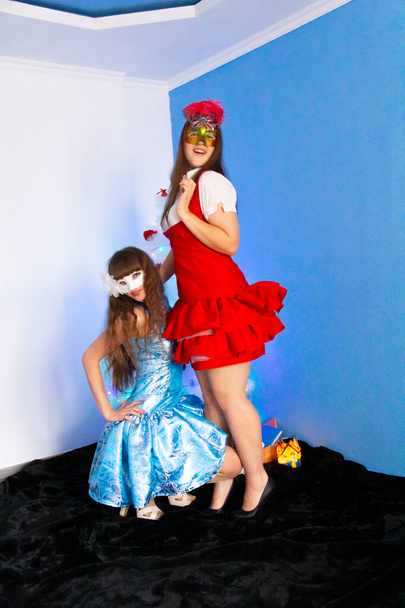 A girl in a blue dress is squatting, a girl in a red dress is standing. Joy on their faces - Foto, Imagen