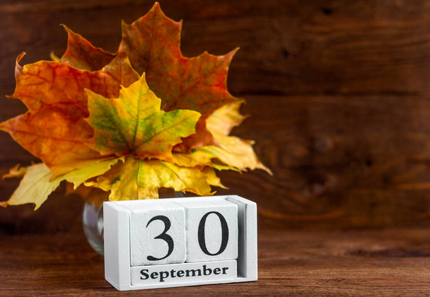 30 вересня за дерев'яним календарем і осіннім букетом з кленового кольорового листя. дата осіннього місяця. Концепція Золота осінь
. - Фото, зображення