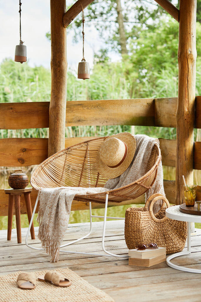 Interior design of summer gazebo by the lake with stylish rattan armchair, coffee table, sofa, pillows, plaid and elegant accessories in modern decor. Summer vibes. Chillout. Template. - Photo, image