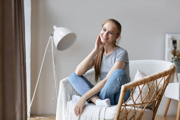 Relaxed young woman on modern chair enjoying morning at home. Good weekend. - Foto, Imagem