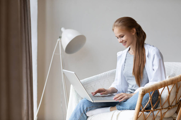 Woman  freelancer using laptop while sitting on comfortably chair at home. Remote work or study. - Foto, imagen