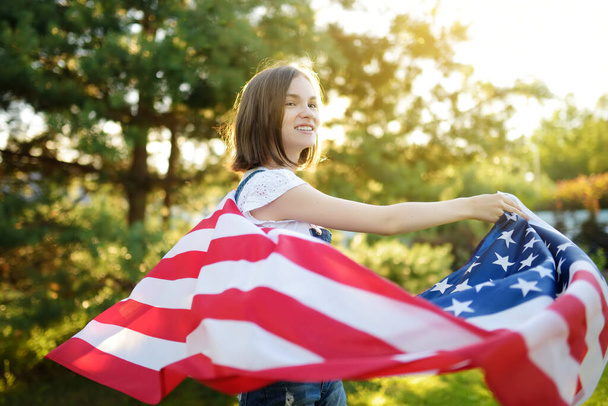 Cute young girl holding American flag outdoors on beautiful summer day. Independence Day concept. Child celebrating national holiday. Remembrance day. - Valokuva, kuva