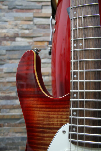Частина гітари на фоні каменю
 - Фото, зображення