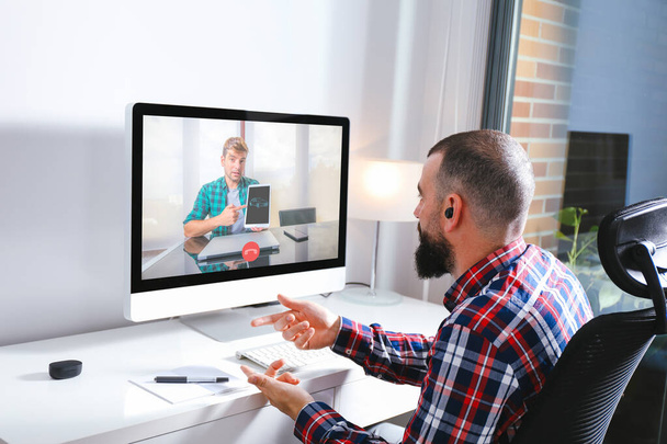 Work from home and virtual meeting concept. Young man in front of computer having video conference with coworker. They are discussing job issues - Foto, immagini