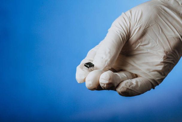 La main dans un gant blanc tient une puce. Chipisation de personnes après un coronavirus épidémique. Espace de copie - Photo, image