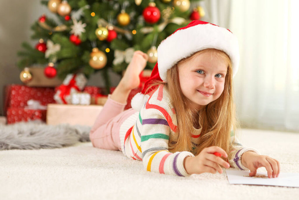 Noel arifesindeki küçük kız Noel Baba 'ya bir mektup yazıyor. - Fotoğraf, Görsel