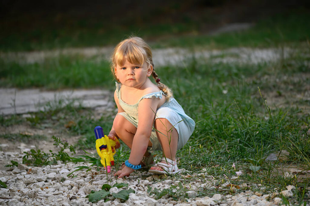 Little blonde girl with a water pistol - Photo, Image