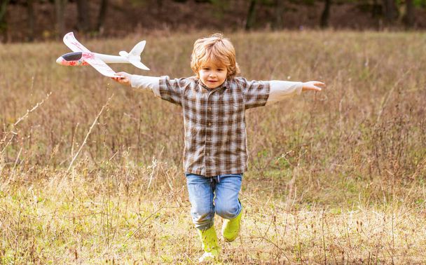 Ragazzino con l'aereo. Il bambino sogna di fare il pilota. Bambino che gioca con aeroplano giocattolo. Bambino felice che gioca - Foto, immagini