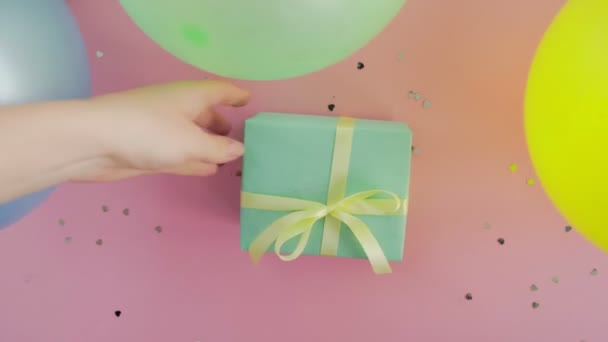 Mujer putts Navidad cumpleaños regalo caja envuelta en papel verde sobre mesa rosa - Metraje, vídeo