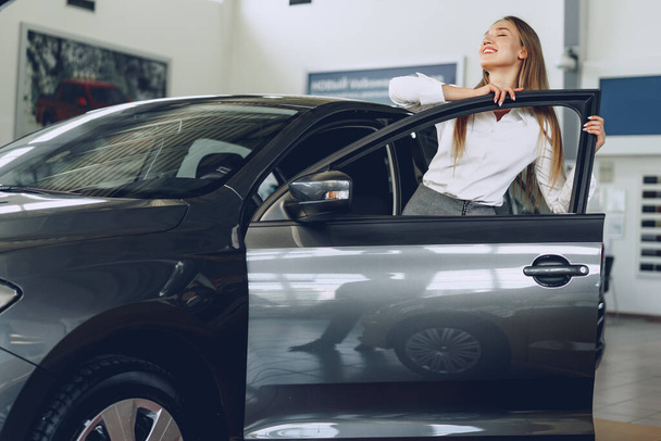 Beautiful young woman touching her new car with pleasure - Zdjęcie, obraz